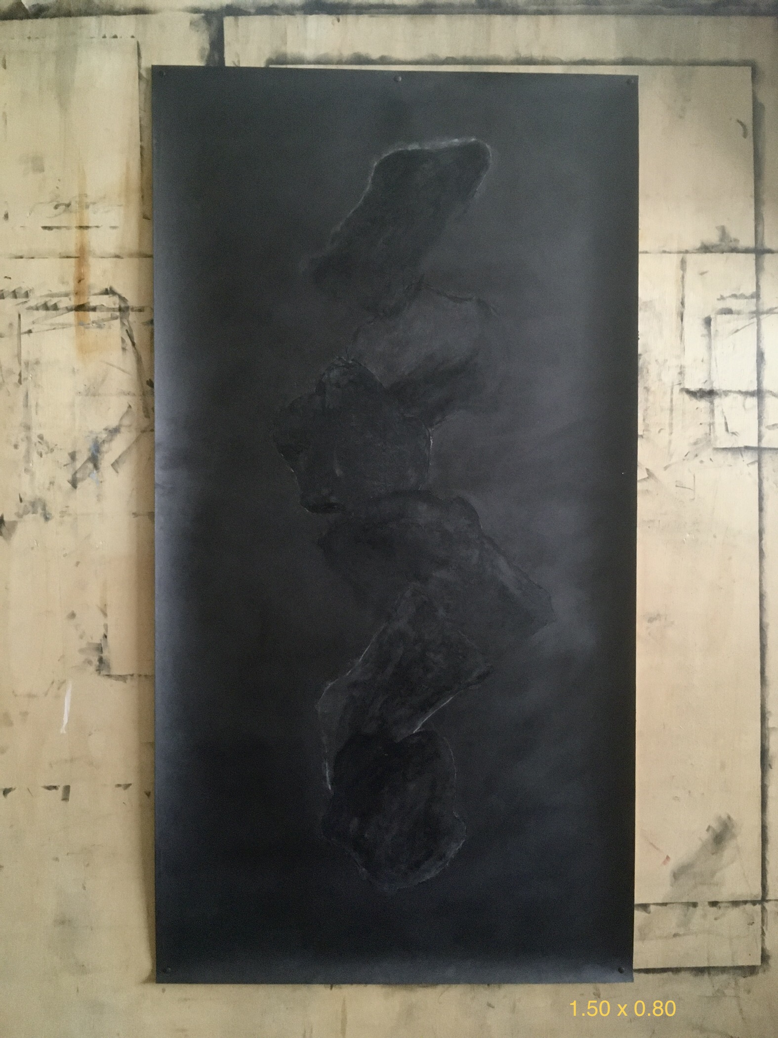 Pintura escura vertical sobre parede de ateliê.